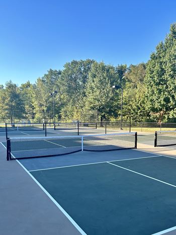 a tennis court with a net on it at The Madison Apartment Homes in Texas 75703